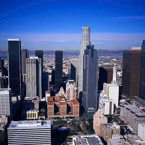 This image shows a cityscape with numerous tall buildings under a clear blue sky, densely packed to form a bustling downtown area.